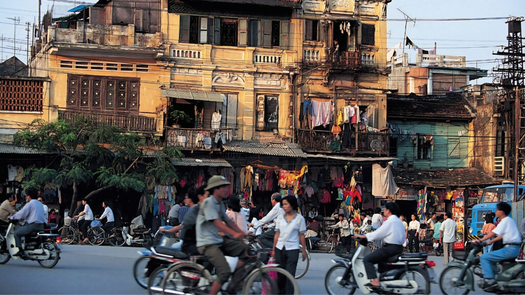 Transportation in Vietnam: How to Get Around Vietnam Without Losing Your Mind (2026 Guide) 2 Busy Hanoi street with scooters and tourists crossing road in Vietnam
