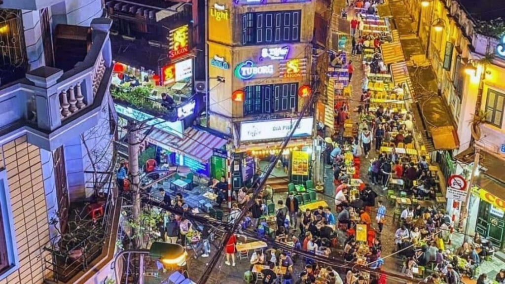 Vietnam Nightlife Guide 2026: Best Bars, Rooftops, Clubs & Night Markets 🇻🇳 5 Locals and travelers drinking bia hoi on Ta Hien Beer Street in Hanoi Vietnam