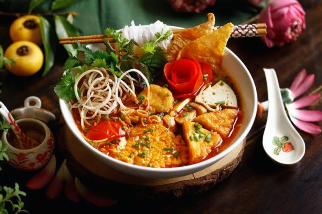 Vietnamese vegetarian bun rieu noodle soup with tomatoes tofu and herbs