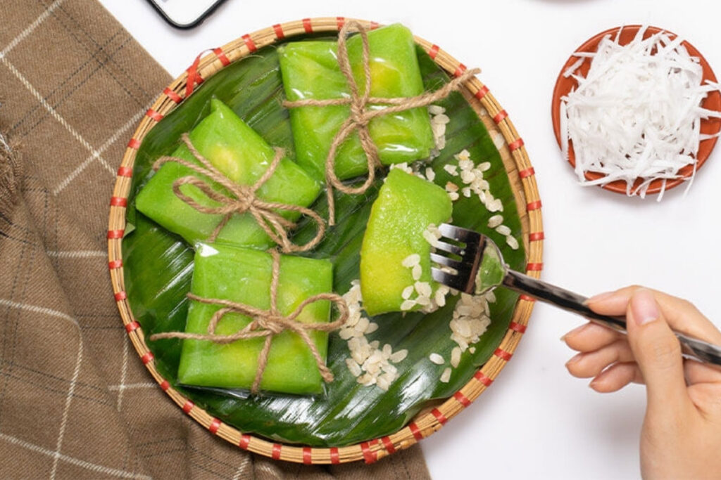 Best Vietnamese Desserts: 20 Sweet Treats Every Traveler Should Try in Vietnam 11 Traditional Hanoi bánh cốm made with young green rice and sweet mung bean filling, displayed on a bamboo tray.