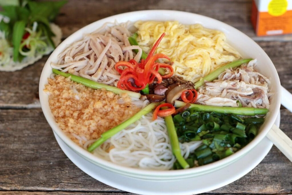Hanoi Food Guide: 15 Must-Try Dishes & Where to Eat Like a Local 8 Elegant bowl of Hanoi bun thang with shredded chicken, egg, Vietnamese sausage, herbs, and clear broth.
