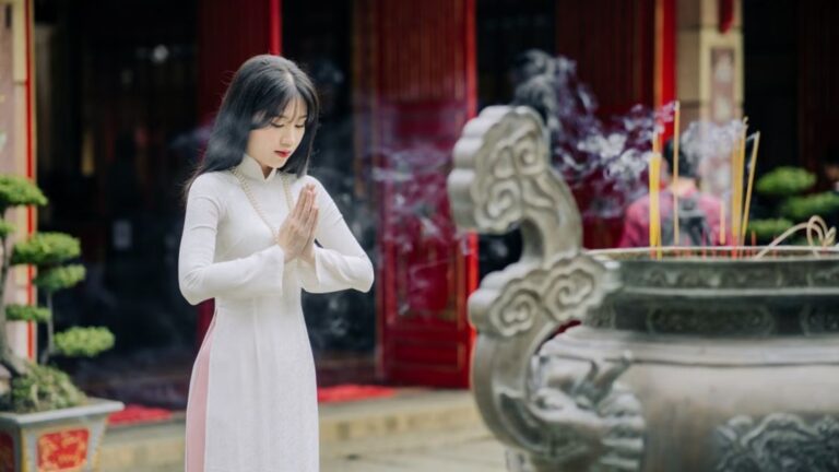 Vietnamese woman offering incense inside an ancient Buddhist pagoda in Vietnam