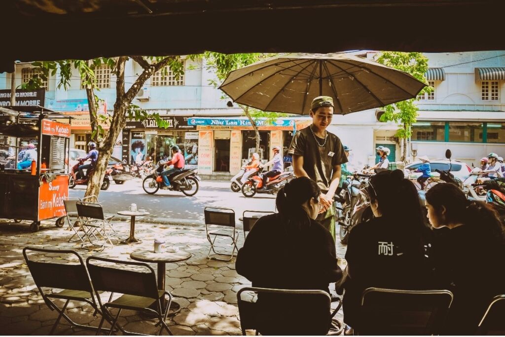 Locals drinking coffee at a sidewalk cafe in Hanoi Vietnam