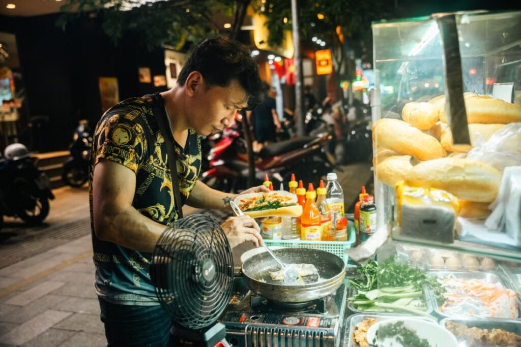 Vietnamese street food vendor preparing a banh mi sandwich