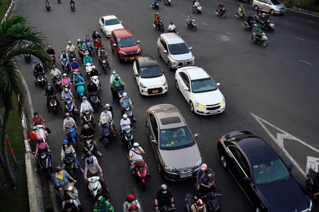 Motorbikes and cars moving through a busy street in Vietnam