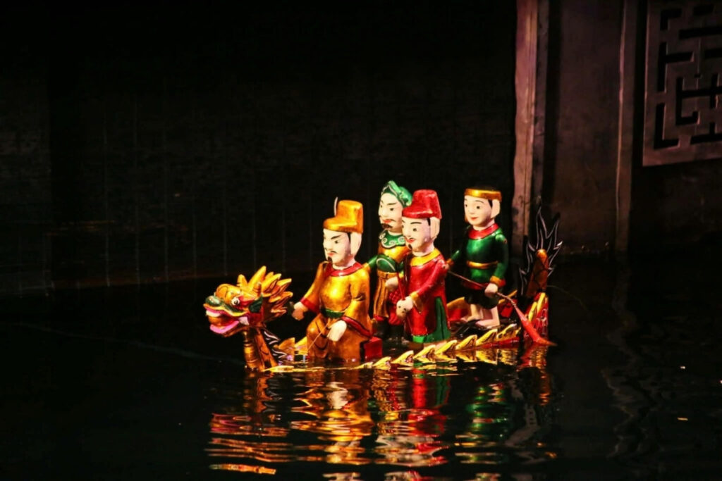 Vietnamese Water Puppet Show Guide: What to Expect & Where to Go 4 Wooden puppets performing on the water stage during a Vietnamese water puppet show