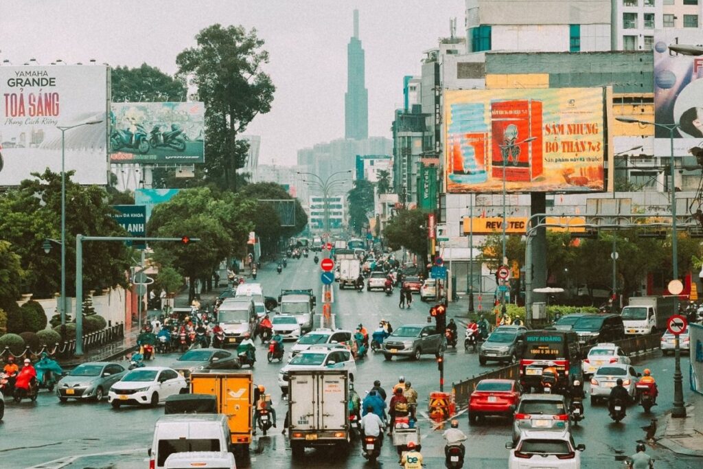Motorcycles and cars moving through a wide intersection in Ho Chi Minh City