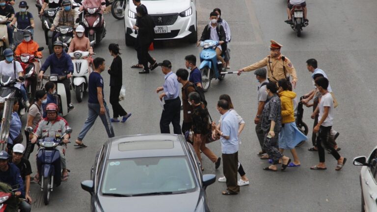 Pedestrian crossing the street in Vietnam, with motorcycles passing