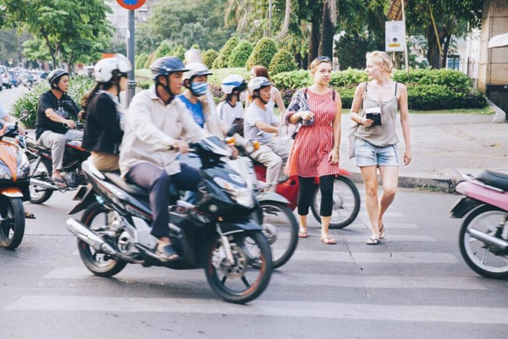 Pedestrian crossing a busy street in Vietnam with motorcycles approaching from different directions