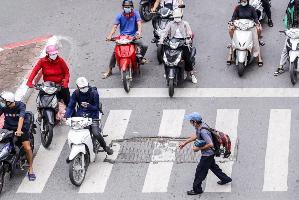 Pedestrian watching motorcycle traffic before crossing a street in Vietnam
