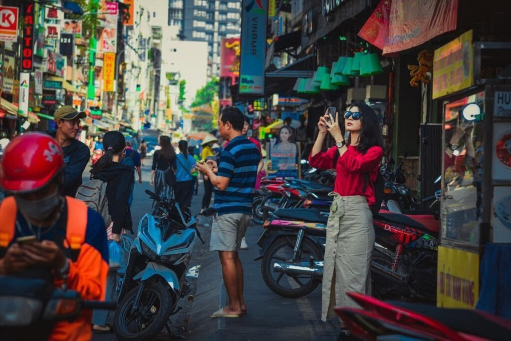 Pedestrian using a phone near busy motorcycle traffic in Vietnam